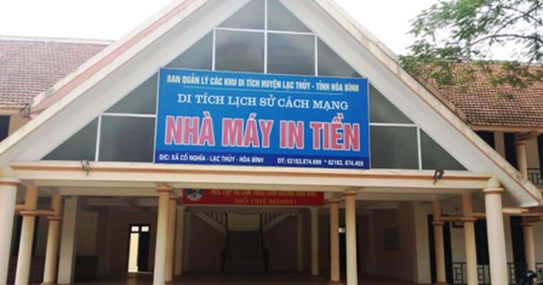 Đây là hình ảnh của Di tích lịch sử cách mạng Nhà máy in tiền, tọa lạc tại xã Cố Nghĩa, huyện Lạc Thủy, tỉnh Hòa Bình. Công trình mang kiến trúc truyền thống với mái ngói đỏ và biển hiệu nổi bật ghi rõ tên di tích. Đây từng là địa điểm in tiền phục vụ kháng chiến, đóng vai trò quan trọng trong việc ổn định tài chính thời kỳ đầu của nước Việt Nam Dân chủ Cộng hòa. Ngày nay, nơi đây được bảo tồn như một địa chỉ đỏ để giáo dục truyền thống yêu nước và lòng tự hào dân tộc.